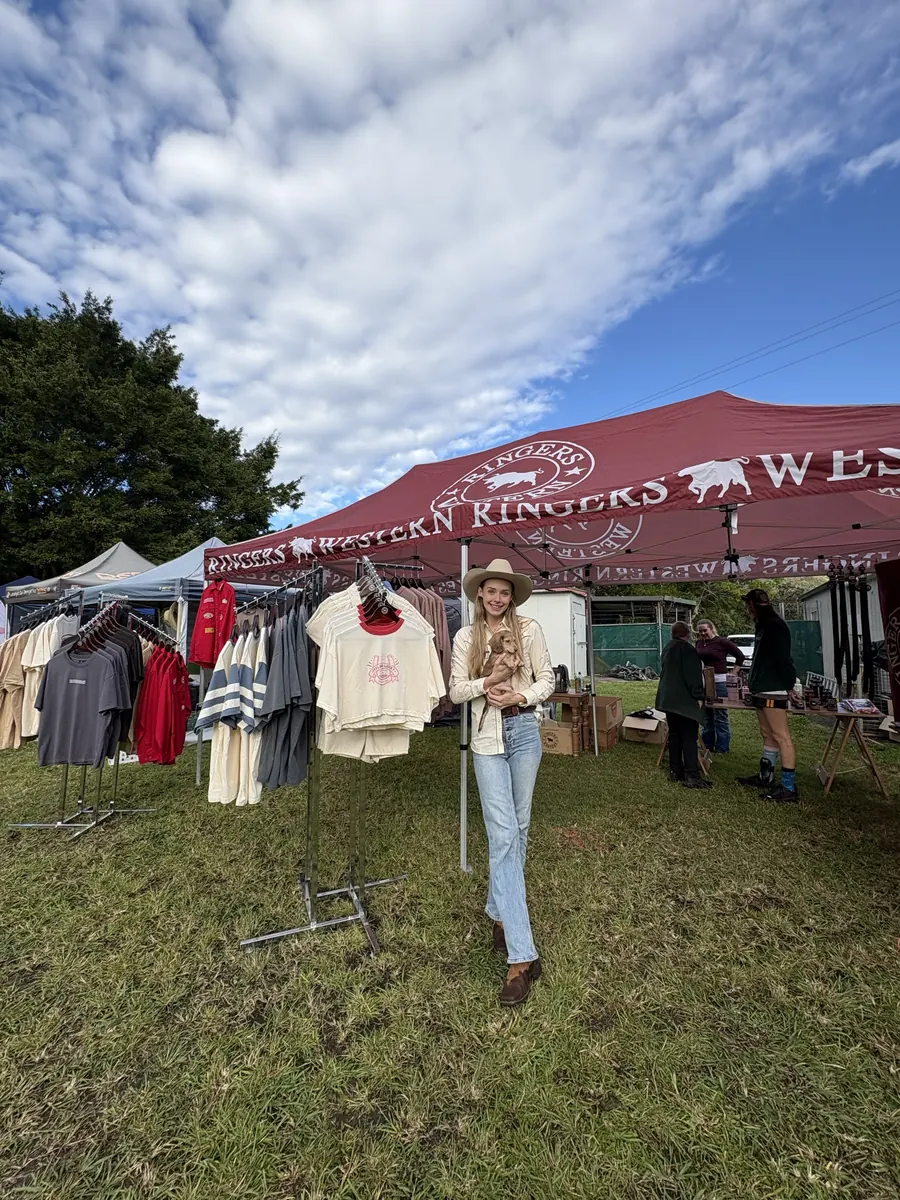 Western wear on racks under the Ringers Western marquee, with visitors walking the row