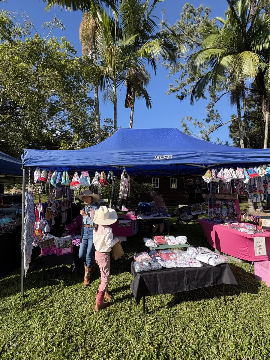 A shopper browsing clothing racks under a blue marquee at the Cowboys and Country market