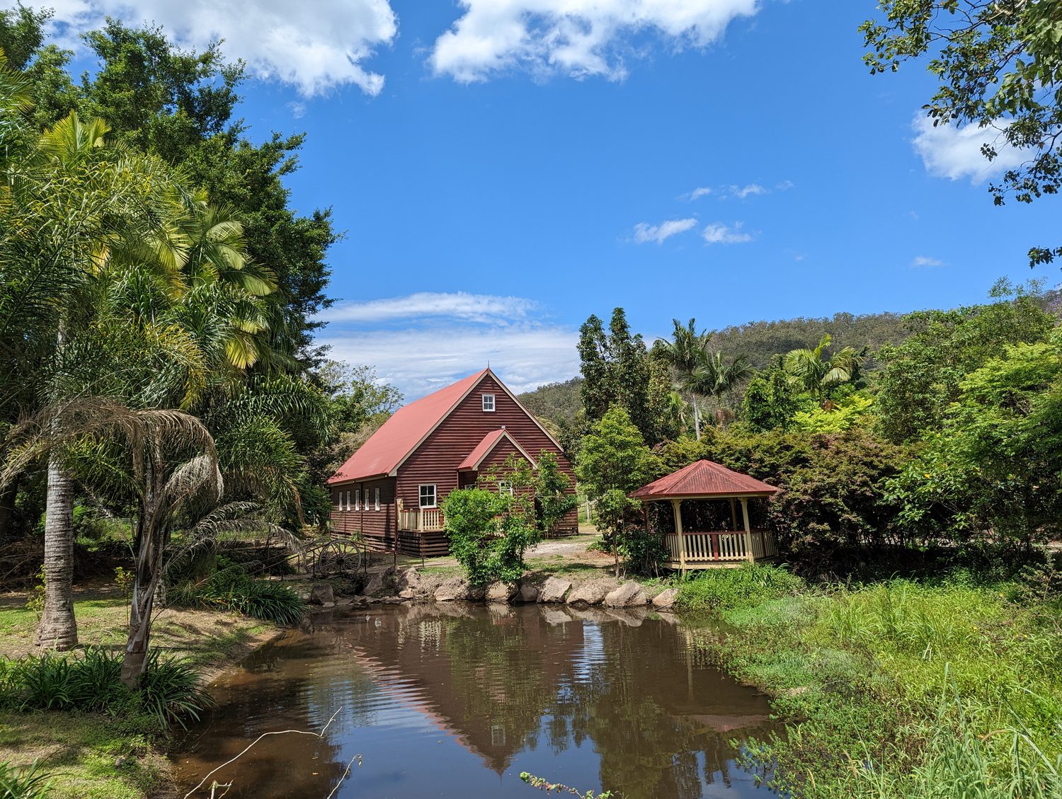 The red timber wedding chapel and rotunda reflected in the pond at Historic Rivermill