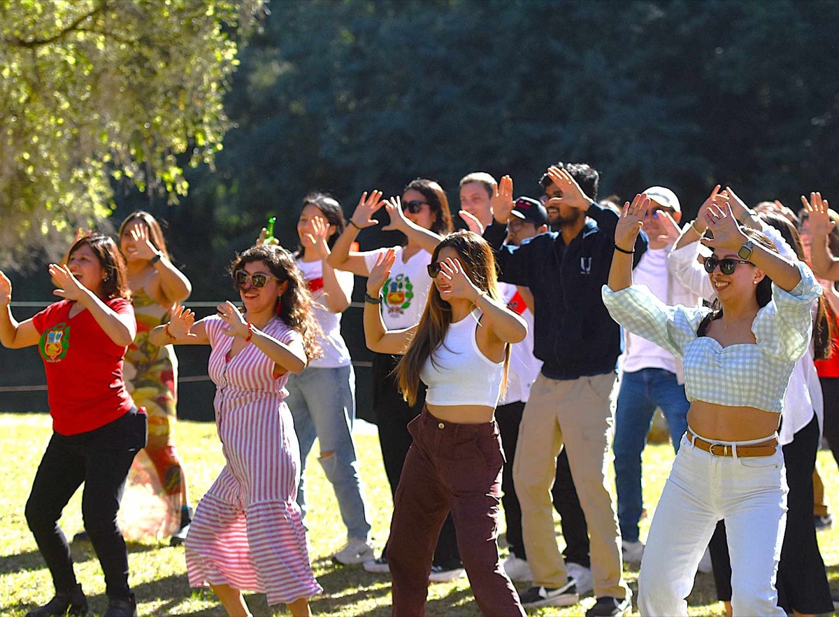 A work group dancing together on the sunlit lawn at Historic Rivermill