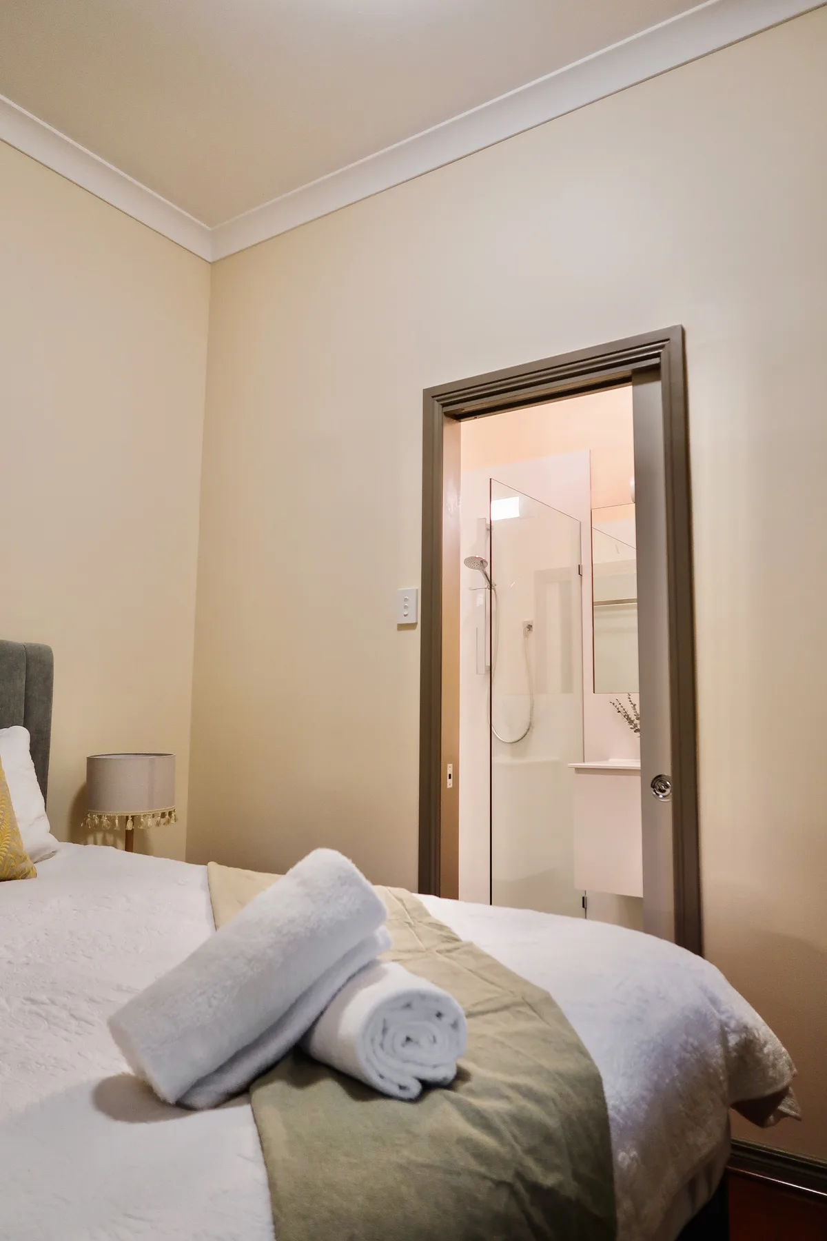 A bedroom with its own ensuite, the shower and vanity seen through the doorway