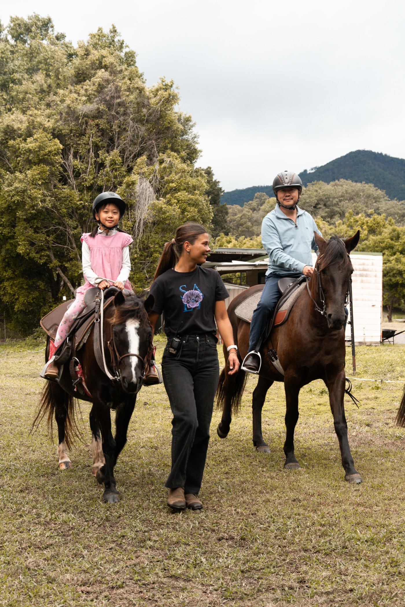 A dad and his daughter riding gentle horses with a guide at Historic Rivermill