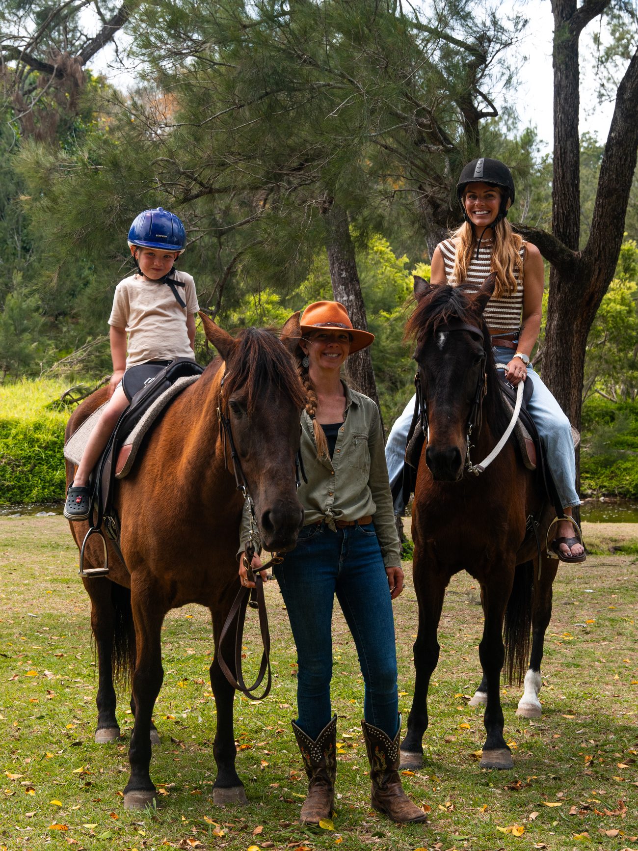 A young rider and an adult rider each on their own horse, with their guide standing between them