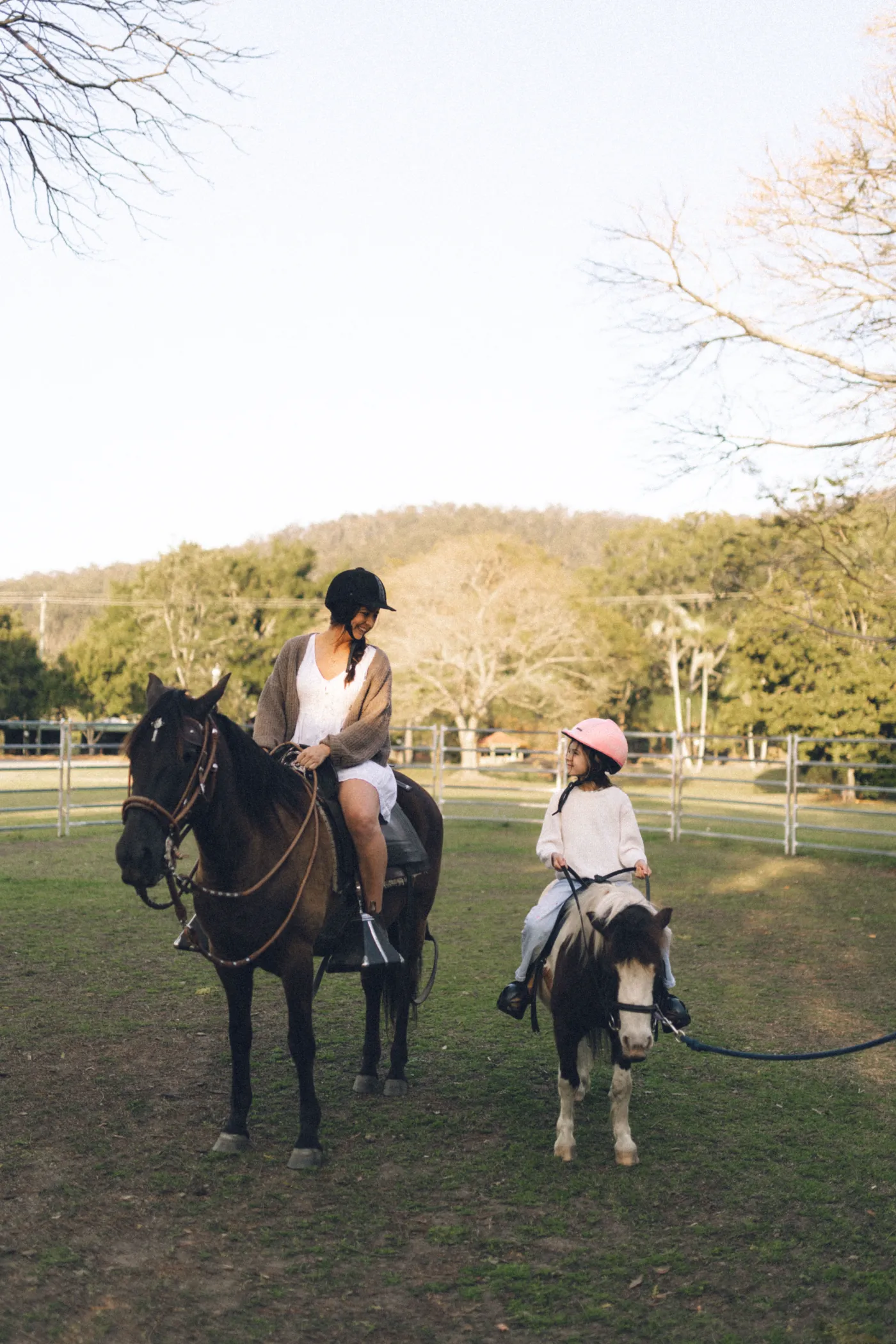 A parent on a Paso horse riding beside a child on a pony