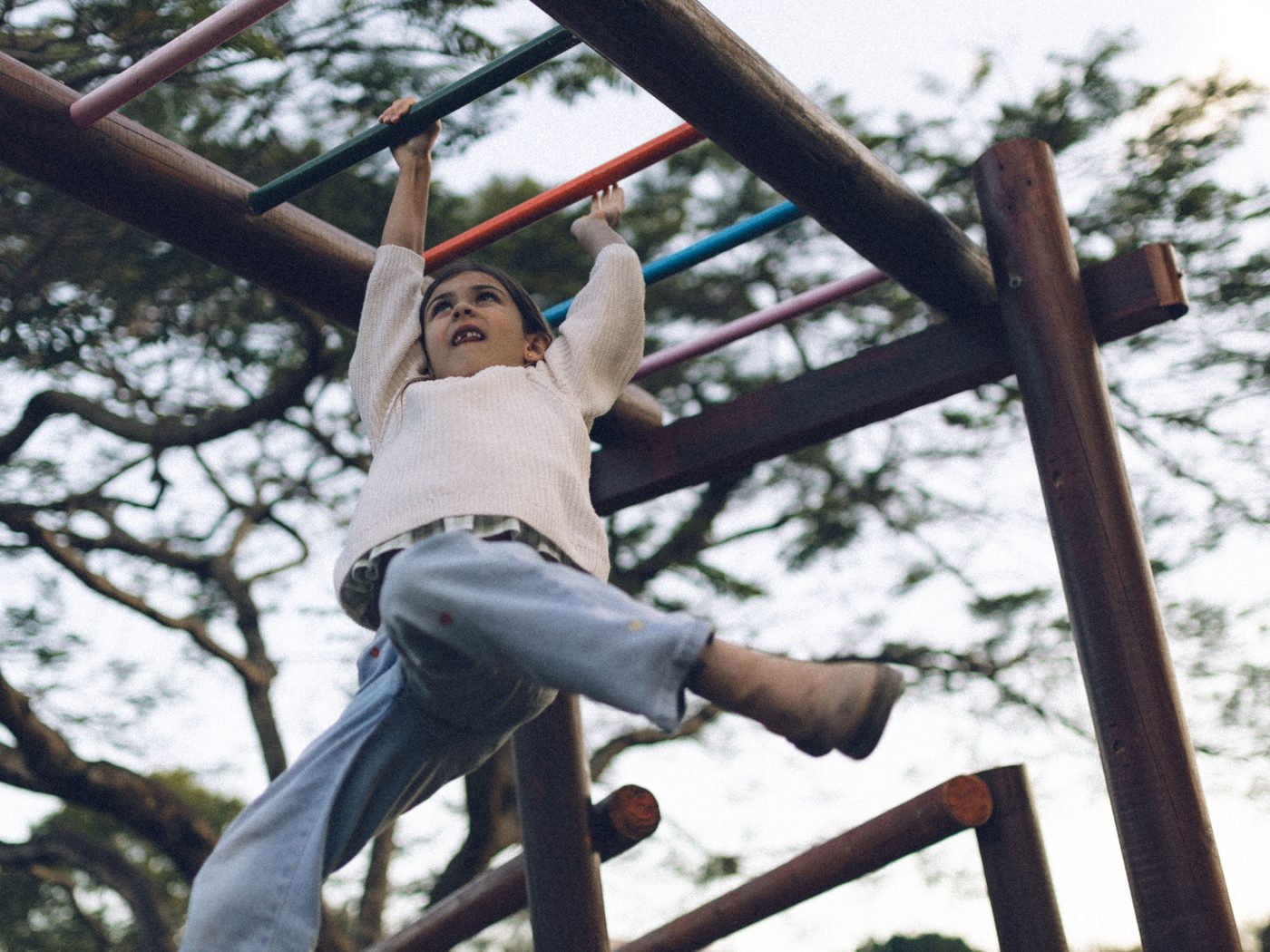 A girl swinging hand over hand along the monkey bars at the Historic Rivermill playground