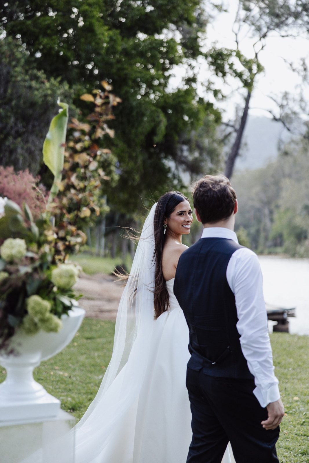 A bride glancing back over her shoulder beside the river